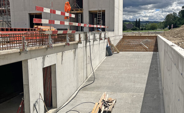 Betonierte Zufahrtsrampe zur Tiefgarage neben dem Rohbau des neuen Büro- und Lagergebäudes.