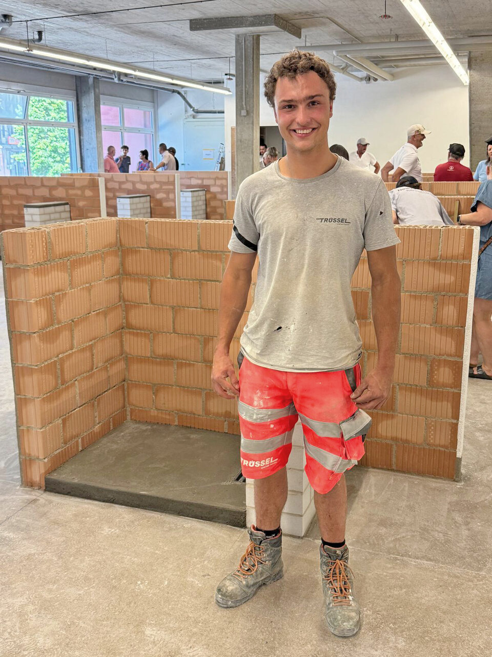 Kilian Minder von der Trüssel AG vor einer gemauerten Wand an der Lehrabschlussprüfung.