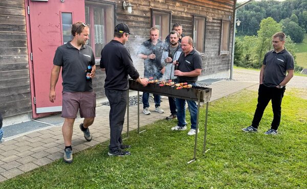 Teilnehmer stehen gemeinsam am Grill während des Hornusser-Events.